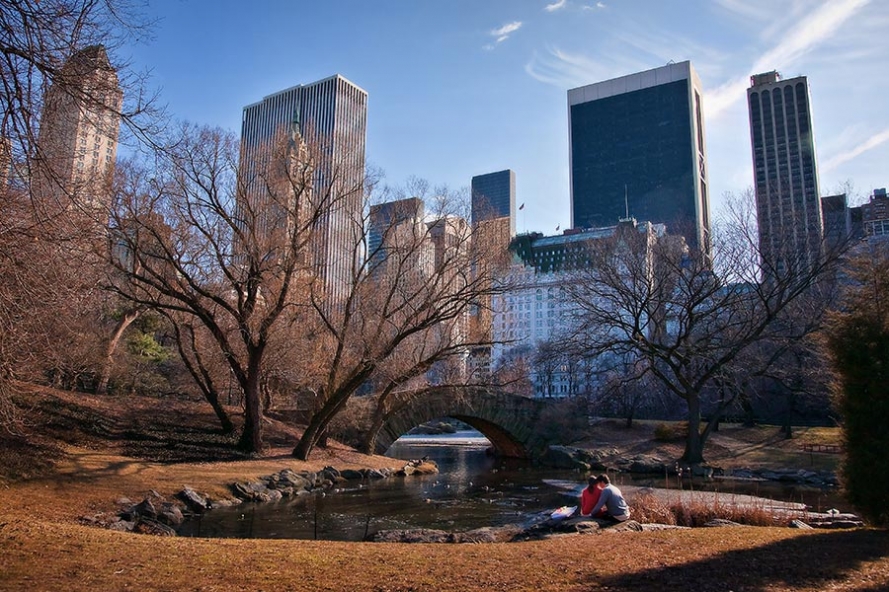young couple sit by a lake in Central Park Manhattan New York