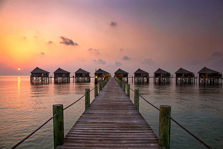 sunrise over water villas on the island of komandoo in the maldives
