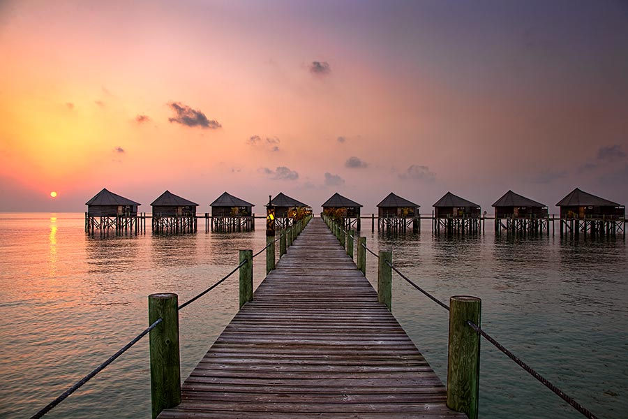 sunrise over water villas on the island of komandoo in the maldives